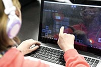 A Fresno Unified student using the touchscreen of a laptop.